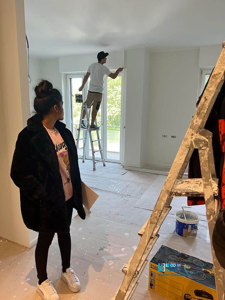 Due persone del Bloom Cleaning Service in piedi su una scala in una stanza, eseguono le pulizie post-costruzione.