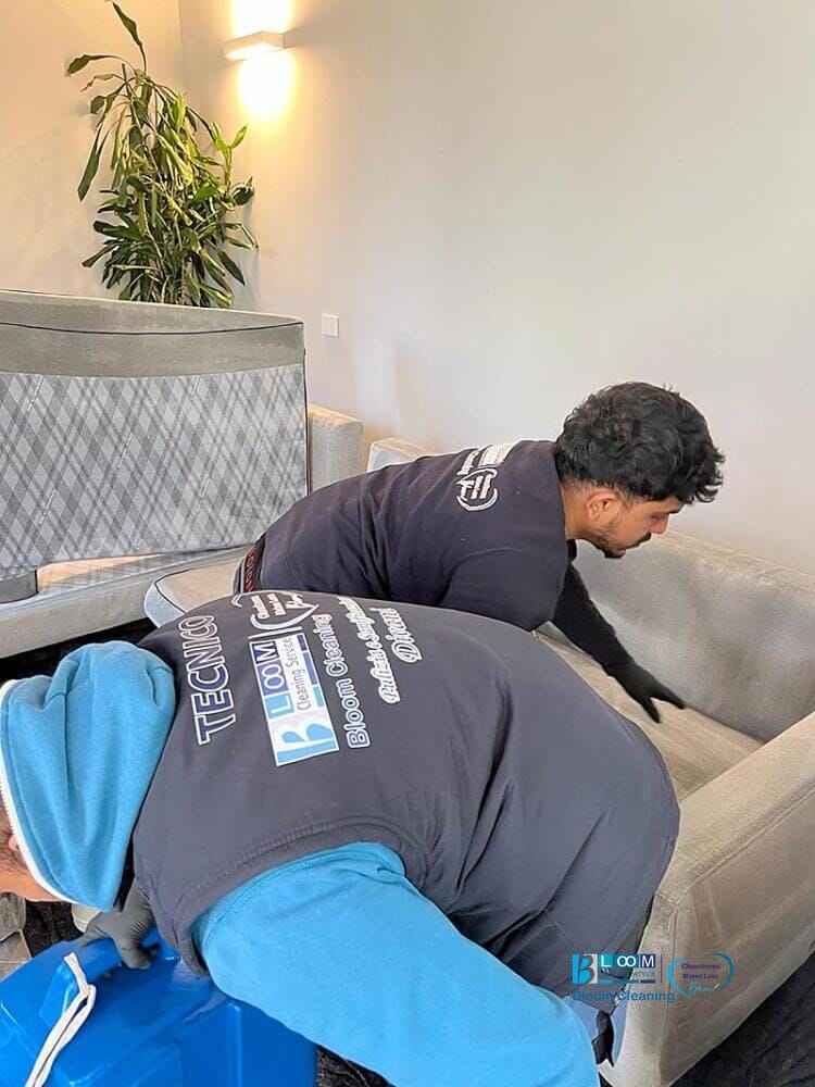 Due uomini che utilizzano il metodo iniezione/estrazione per pulire un divano in soggiorno.