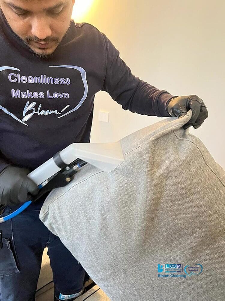 Un uomo che usa un aspirapolvere per pulire un divano.