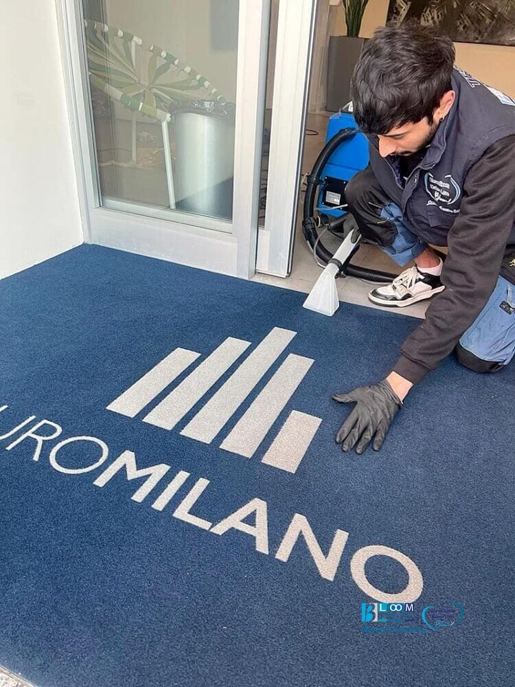 Un uomo che pulisce un tappeto blu con il metodo Rinnova.
