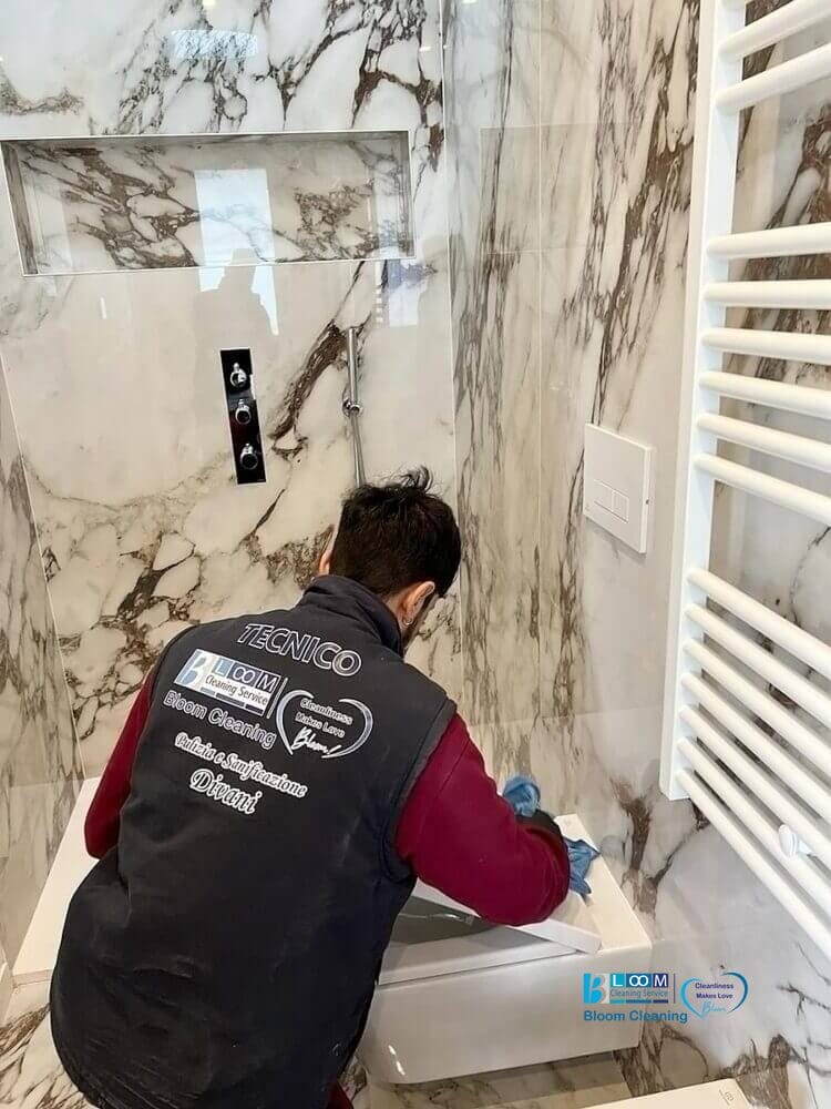 Un tecnico esperto al lavoro per la pulizia di un bagno, con eleganti pareti in marmo a Settimo Milanese.
