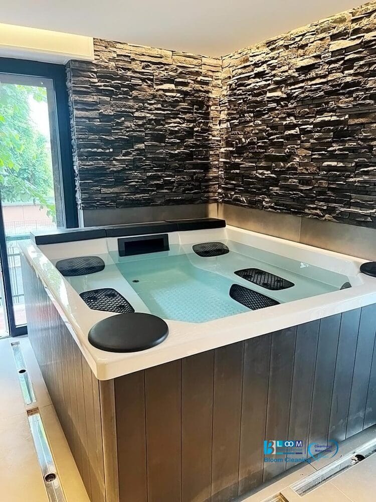 Una vasca idromassaggio interna con una parete in pietra, che offre un luogo di relax tranquillo e privato, perfetto per i servizi di pulizia dopo la fioritura.