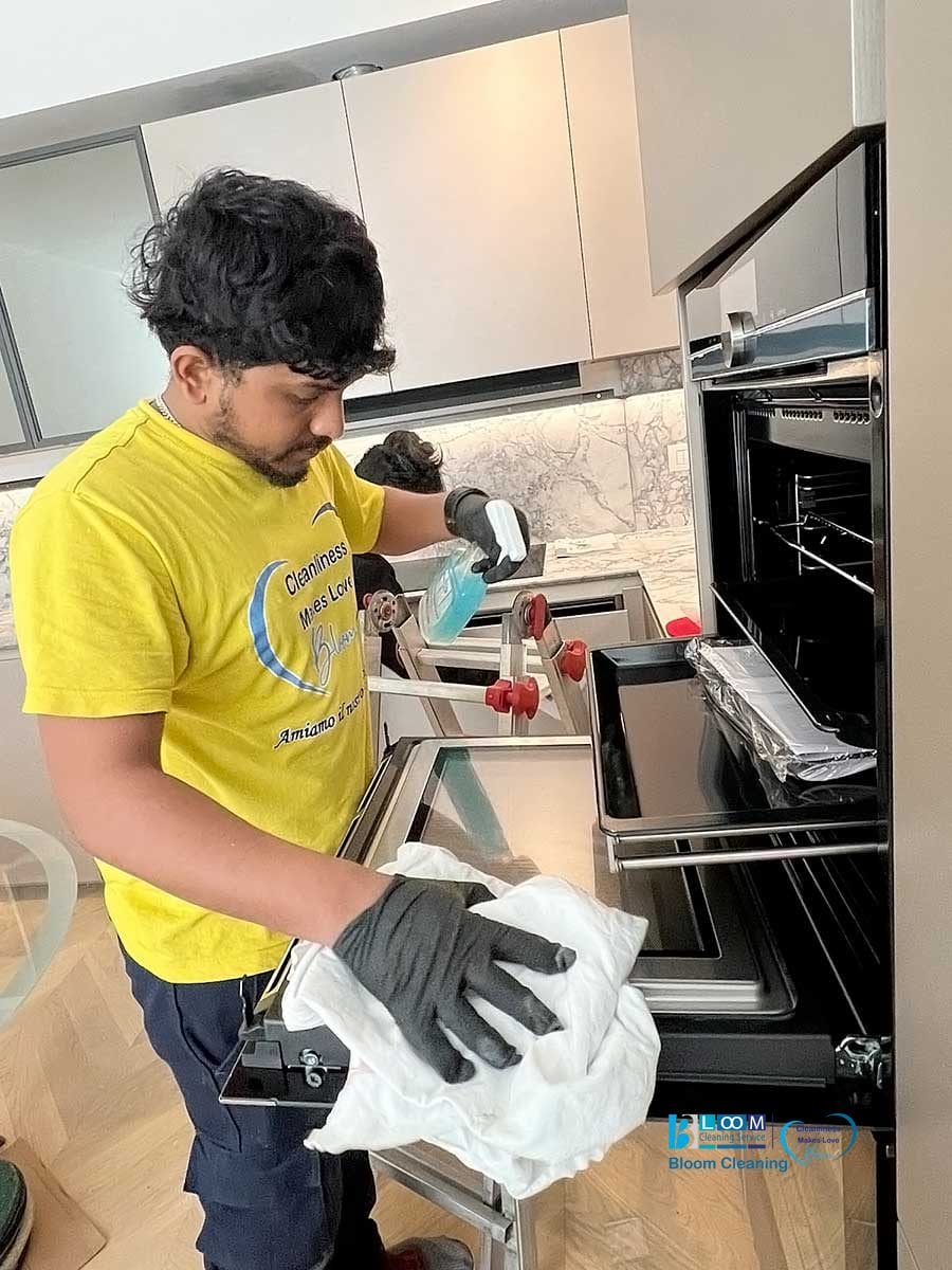 Una persona indossa guanti effettuando la pulizia appartamenti Milano di un forno.