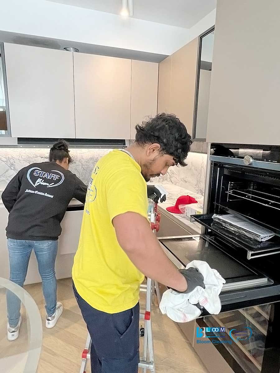 Due persone effettuano la pulizia appartamenti Milano, una al lavandino e l'altra che pulisce il forno.