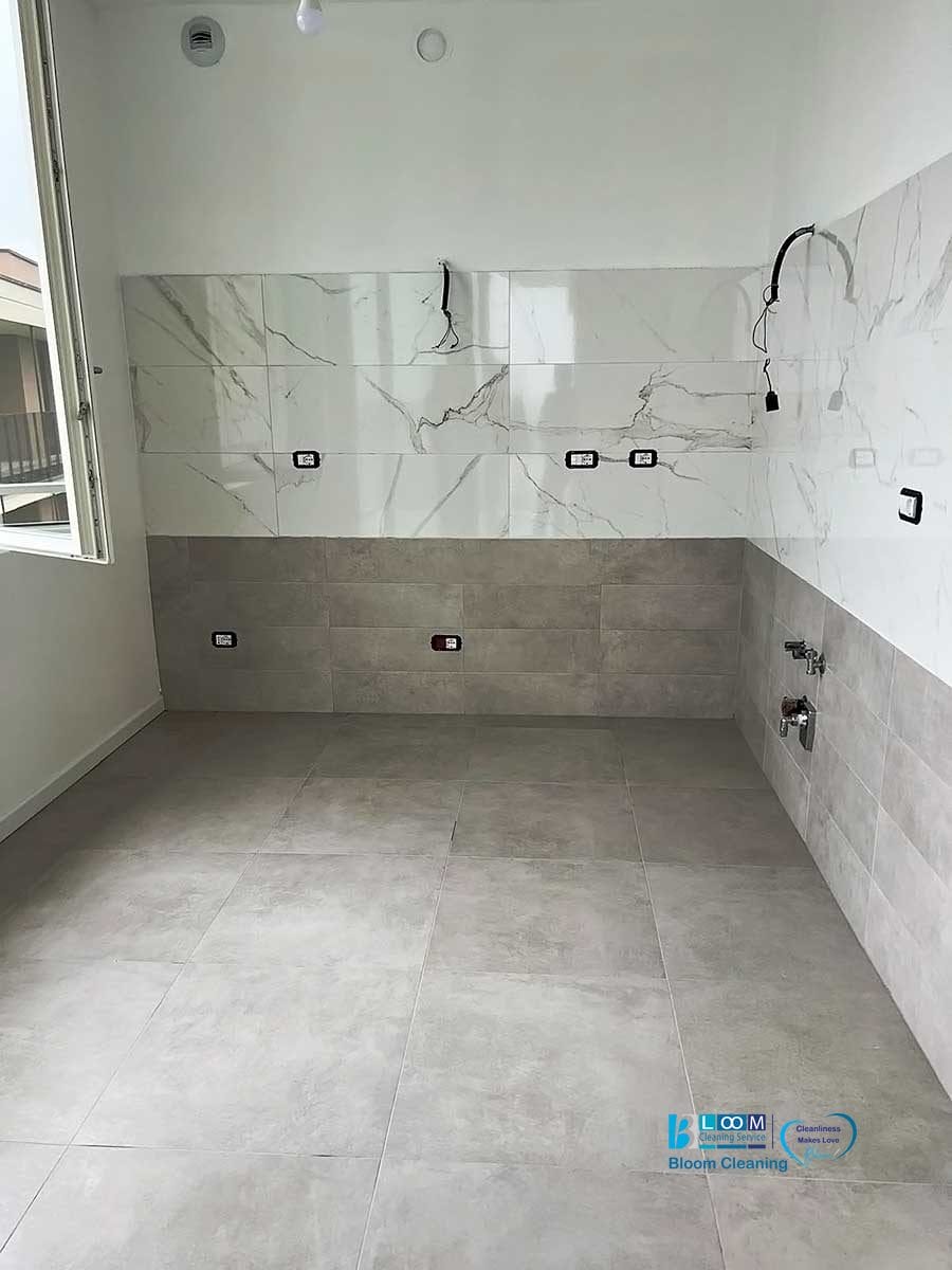 Un bagno moderno in costruzione, caratterizzato da pavimenti in piastrelle grigie, pareti in marmo bianco con dettagli neri e impianti idraulici a vista. Questa fase prepara per gli ultimi ritocchi, compreso un servizio di pulizia specializzato come Bloom Cleaning after