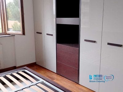 Una camera da letto vuota con un elegante pavimento in legno, una finestra aperta che lascia filtrare la luce naturale, un armadio in legno bianco e scuro e una struttura del letto in metallo in attesa del materasso sono gli elementi su cui Bozza Automatica plasma la sua magia.