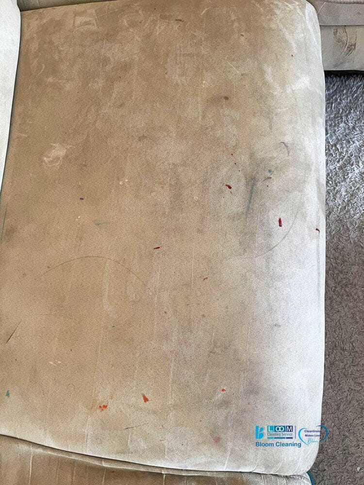 Un cuscino beige per divano, segnato da piccole macchie, riflette un senso di comfort vissuto che non si sottrae alla realtà della bozza automatica, dove la vita è imprevedibile e meravigliosamente imperfetta.