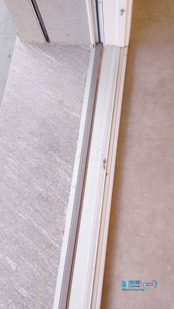 Primo piano di un binario per porta scorrevole in una Villetta ad Assago, che mette in risalto il contrasto tra superfici chiare e scure. La precisione del telaio metallico completa l'allineamento del pavimento, mostrando una sottile trasformazione prima e dopo.