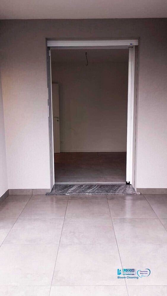 Una porta aperta conduce a una stanza vuota e non arredata, con pavimento piastrellato e pareti semplici, pronta per una trasformazione prima e dopo che ne ridefinirà il carattere e il fascino.