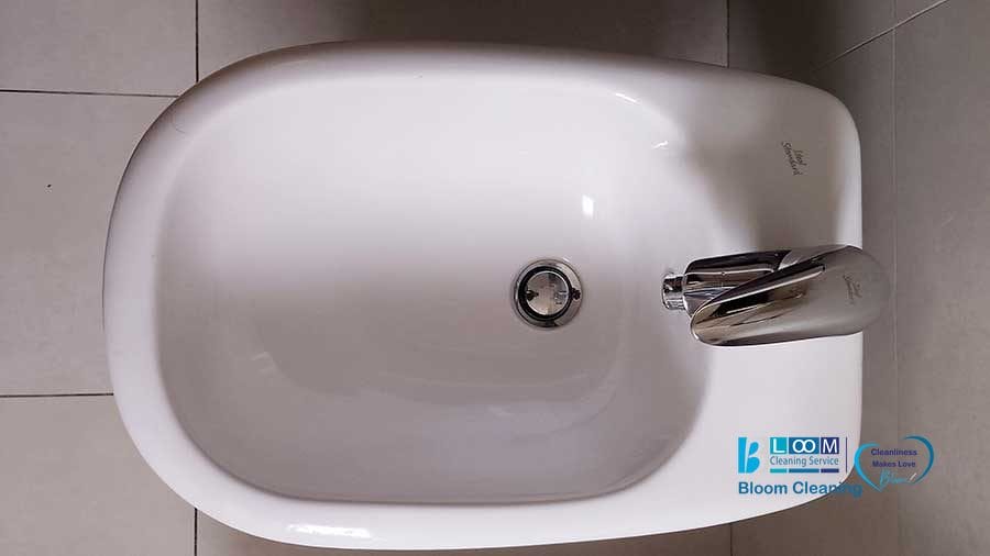 Vista dall'alto di un bidet in ceramica bianca con scarico centrale e rubinetto cromato, il tutto elegantemente sistemato su un pavimento piastrellato. Scoprite la funzionalità raffinata che ricorda i principi di design Bozza automatica.