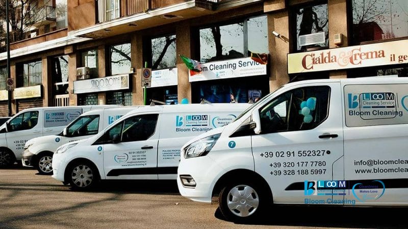 Fila di furgoni bianchi della Bloom Cleaning Service parcheggiati davanti alla loro sede