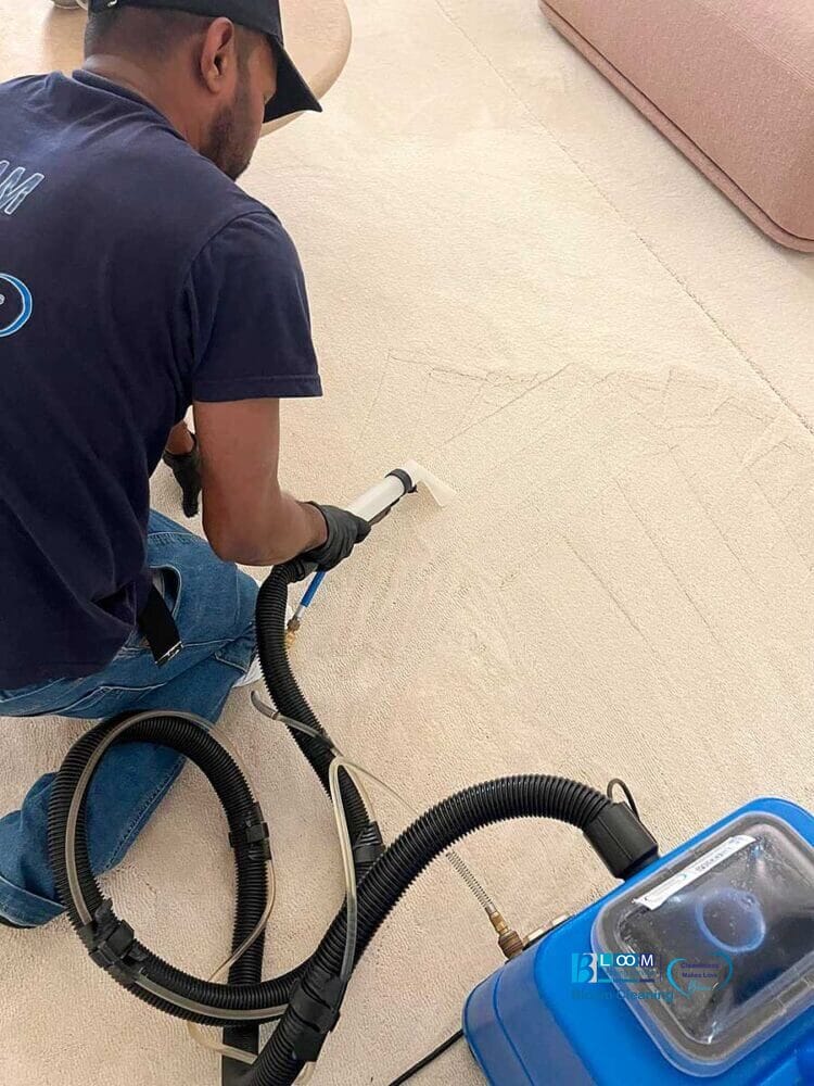 Una persona utilizza una macchina per la pulizia dei tappeti per pulire a fondo un tappeto di colore chiaro, perfetta per chi cerca la pulizia della moquette zona Amendola.