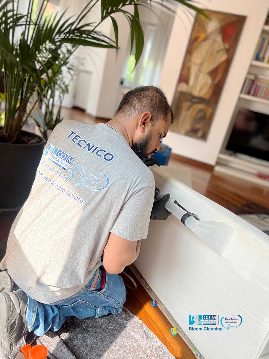 Un tecnico sta eseguendo un lavaggio divani domicilio Monza, pulendo un divano bianco con un aspirapolvere in un soggiorno luminoso e moderno.