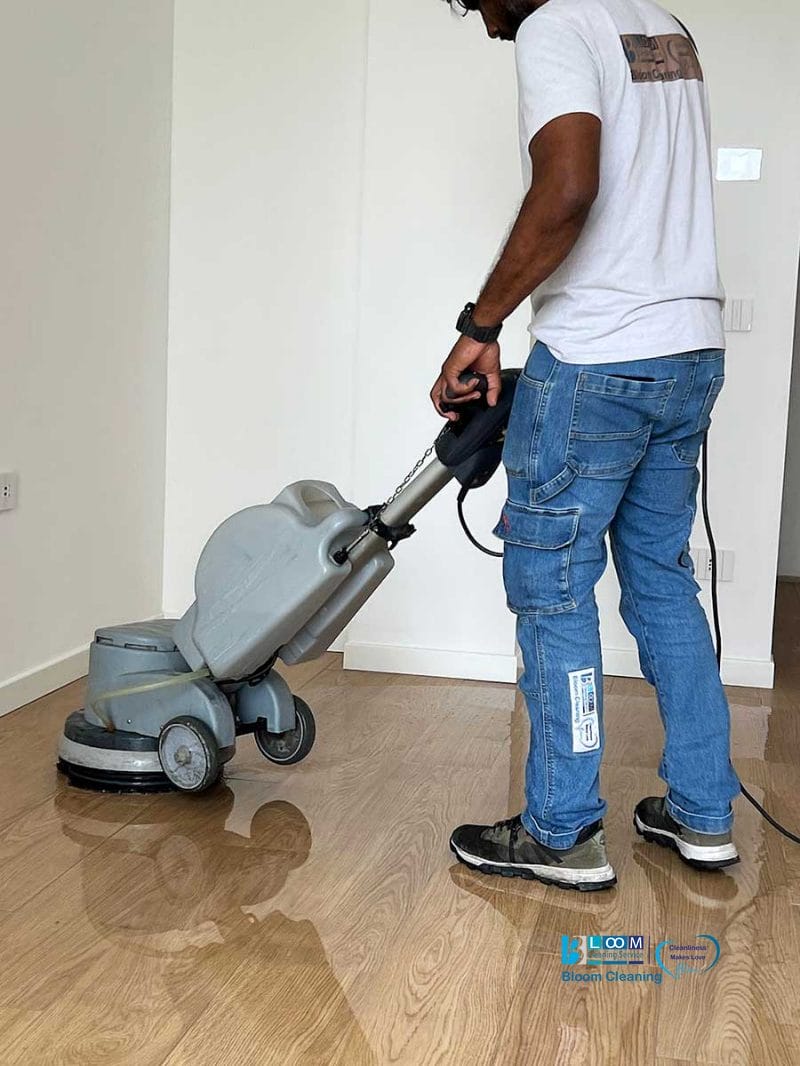 Una persona esegue la pulizia post cantiere Nerviano utilizzando una macchina lavapavimenti su un pavimento in legno in una stanza luminosa.