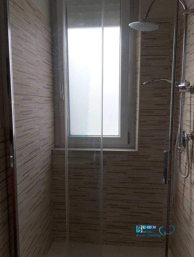 Doccia moderna con porta in vetro, soffione e finestra che lascia entrare la luce naturale: perfetta per chi apprezza la sensazione di freschezza degli appartamenti Bollate.