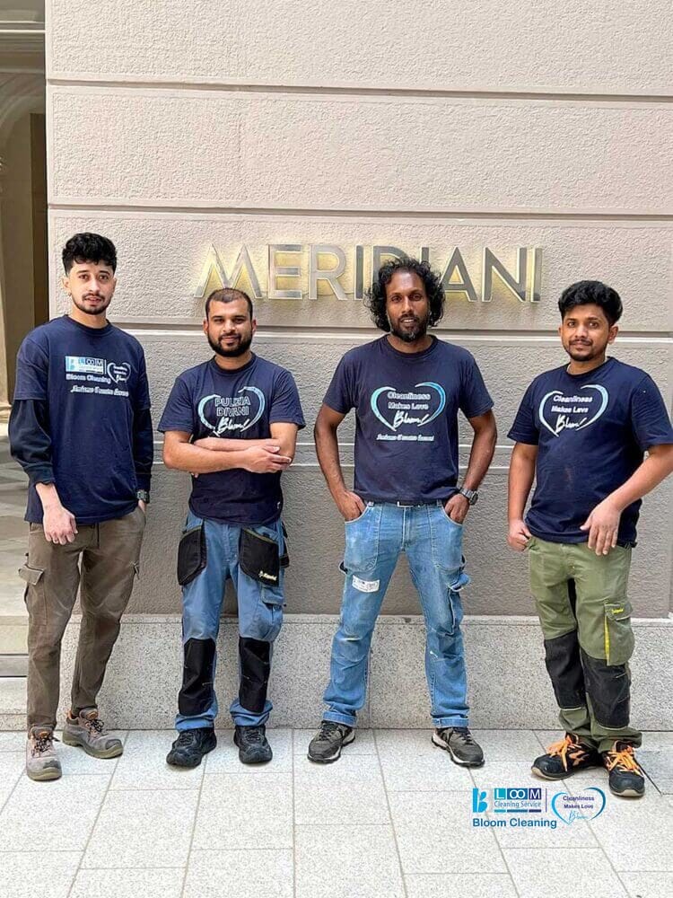 Quattro uomini in tenuta da lavoro si trovano davanti a una parete con l'insegna