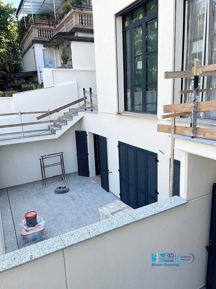 Un edificio moderno in Lombardia con persiane blu e un patio recintato in costruzione, con impalcature e materiali, ideale per le pulizie finali in cantiere prima di accogliere i residenti in questi appartamenti nuovi.